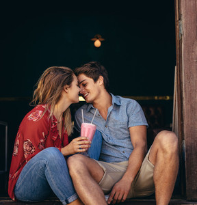 Romantic couple sitting together with a milkshake