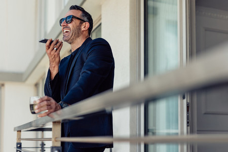 Mature businessman in hotel room balcony talking on phone