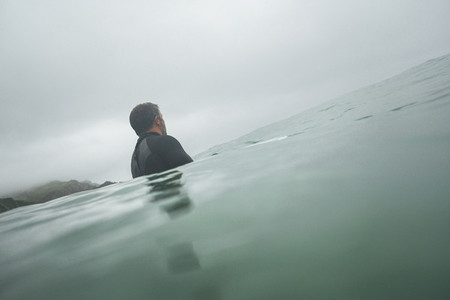 Back view of a surfer waiting for a wave in a cloudy winter day