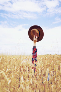 Back view of a young woman in a field of wheat
