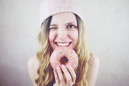 Young and funny blonde woman eating a donut