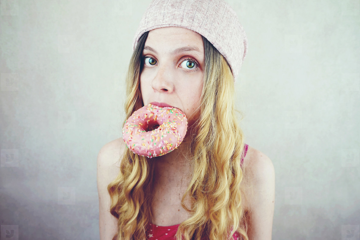 Young and funny blonde woman eating a donut