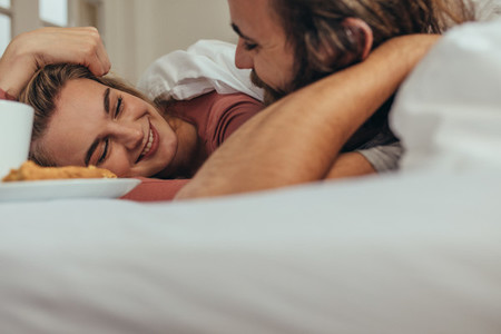 Close up of happy couple lying on bed looking at each other