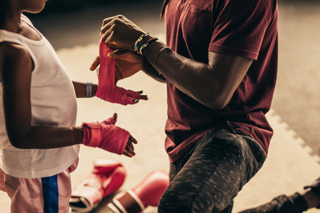 Boxing kid putting on bandages before wearing boxing gloves