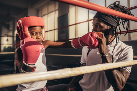 Boxing kid training with his coach at a boxing gym