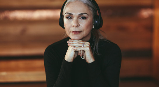 Senior woman listening to music in headphones at cafe