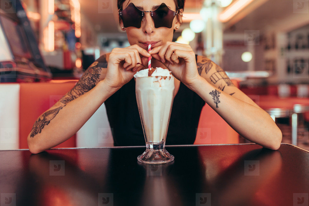 Woman drinking milkshake with a straw sitting at a diner