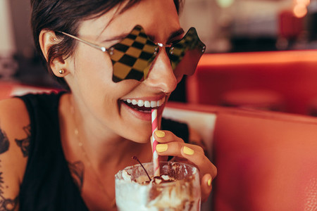 Close up of a woman drinking milkshake with a straw at a diner