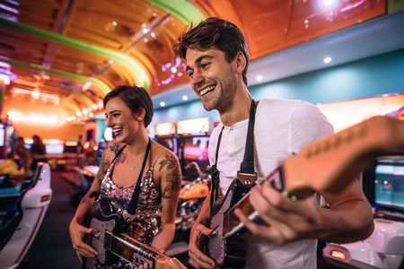 Happy couple playing a guitar arcade game