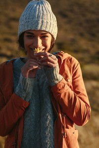 Woman in winter wear smelling a flower on mountain