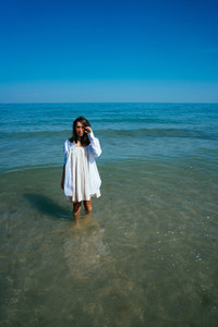 The girl is standing in the sea by the shore