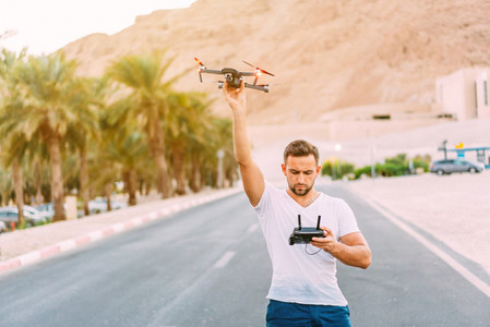 Young man holding drone before flight at nature