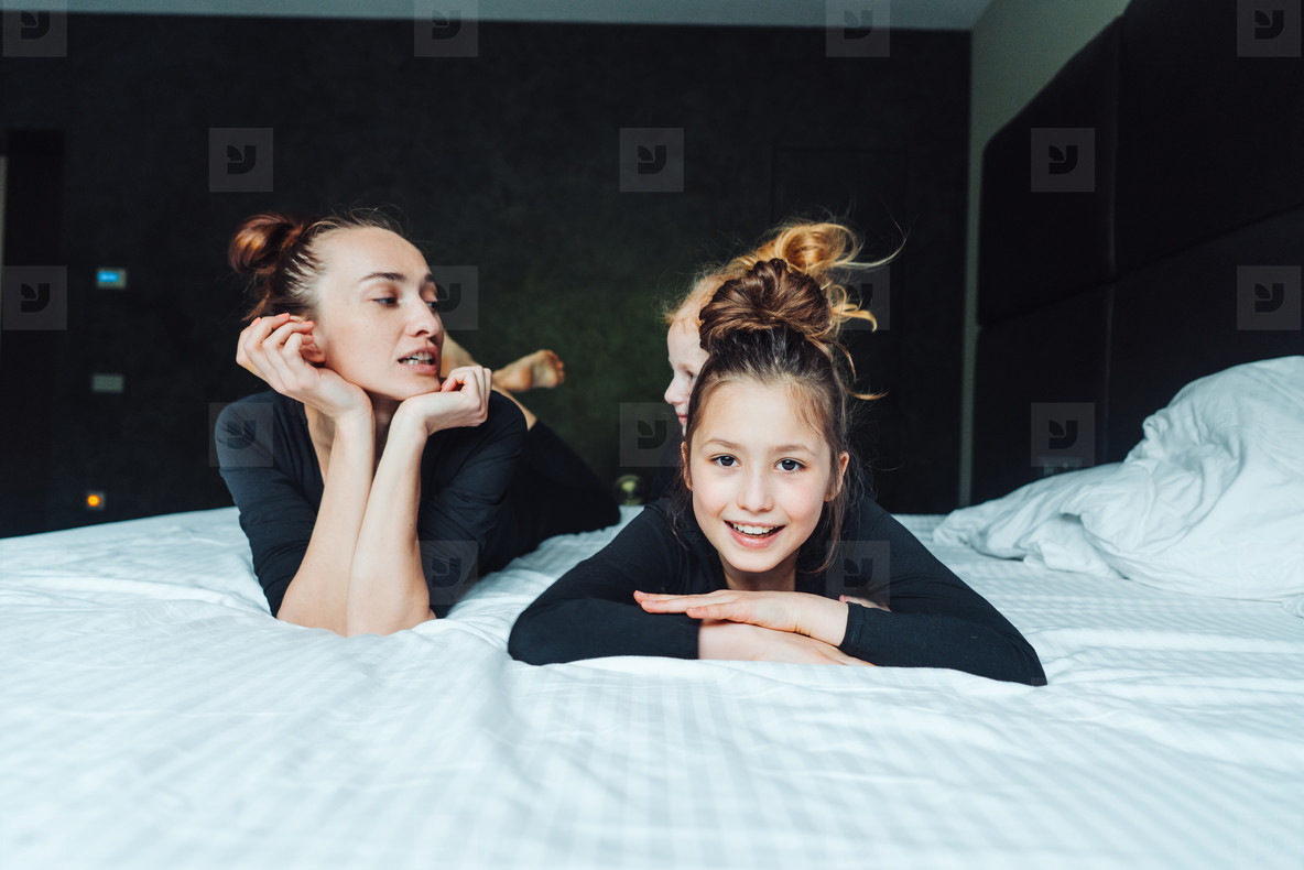 Mom and two daughters have fun on the bed