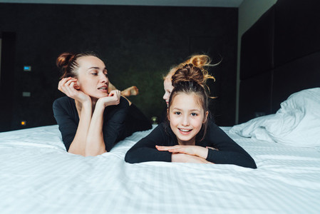 Mom and two daughters have fun on the bed