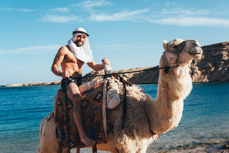 Guy rides on a camel on the beach