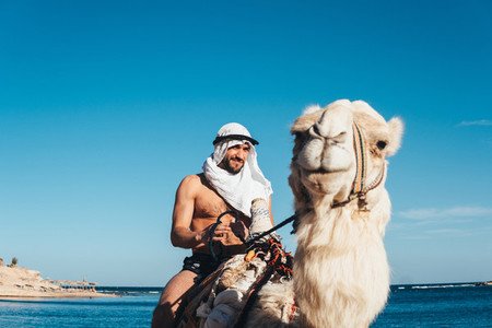 Guy rides on a camel on the beach