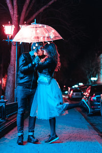 Guy and girl kissing under an umbrella