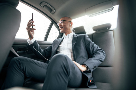 Businessman sitting in car looking at his mobile phone