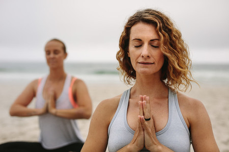 Women practicing meditation and yoga at a beach