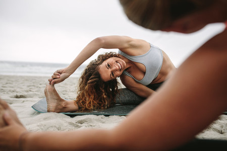 Women practicing yoga positions sitting on the beach