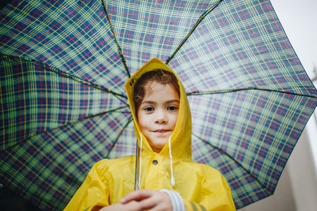 Cute little girl in raincoat with umbrella