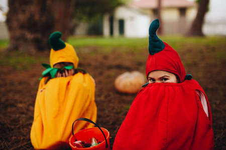 Twin sisters tricking outdoors on halloween