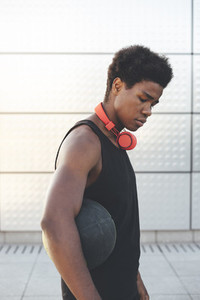 Portrait of young black man in urban scenery at sunset with red headphones and a basket ball