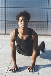 Front view of handsome young black basketball player doing chest press in urban scenery at sunset