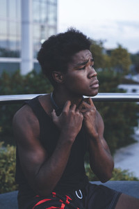 Portrait of young afro man with  wearing black headphones in urban scenery at dusk