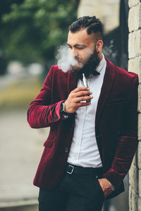 rich man with a beard smokes electronic cigarette