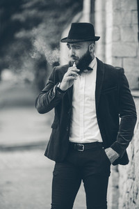 A rich man with a beard smokes electronic cigarette