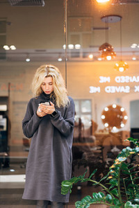 Blonde girl standing with smartphone