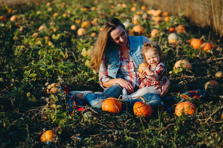 mother and daughter on a field with pumpkins