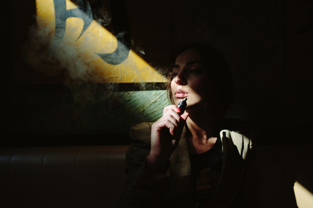 girl sits and smokes electronic cigarette