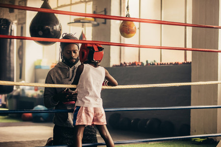Boxing kid standing inside the ring talking to his trainer