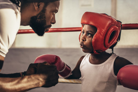 Coach training a boxer kid standing inside a boxing ring
