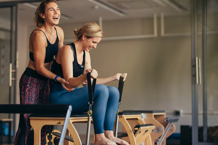 Women laughing while doing pilates workout at a gym