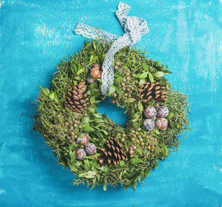 Christmas decorative wreath with pine cones over blue wall background