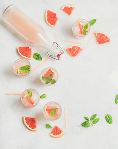 Cold refreshing alcohol cocktail with grapefruit in glasses and bottle