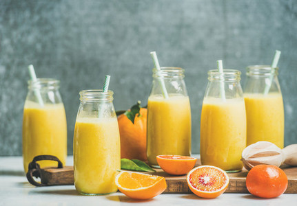 Healthy yellow smoothie in bottles over grey background