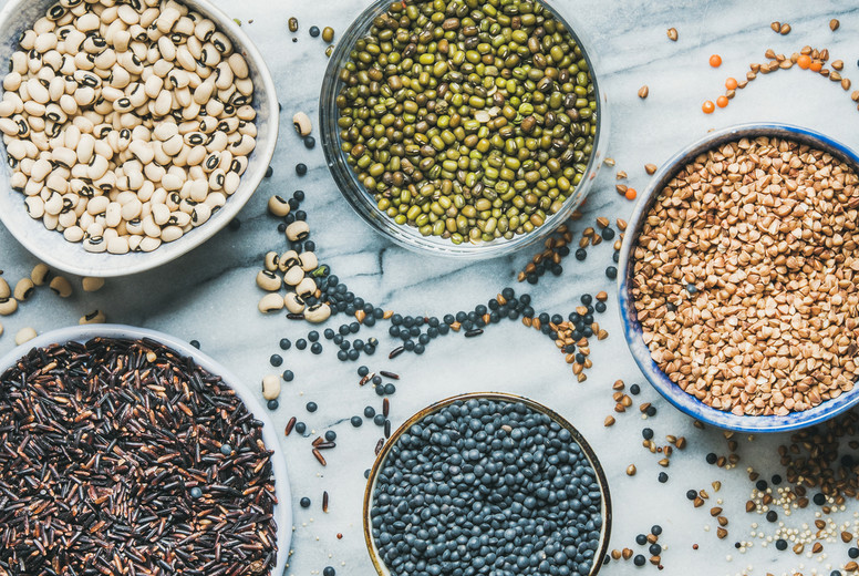 Various raw uncooked grains, beans, cereals in bowls, top view