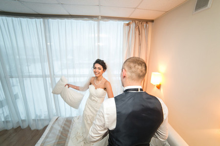 Pillow fight of bride and groom in a hotel room