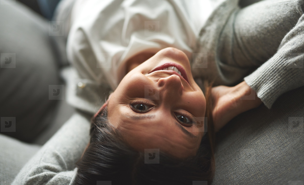 Woman laying on couch looking up smiling