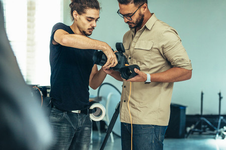 Assistant replacing lens on a camera during a photo shoot