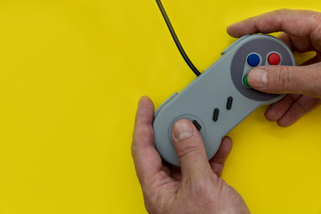 Man playing video game with controller yellow background