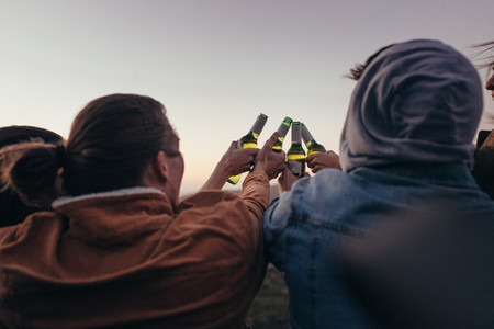 Friends toasting bottles of beer outdoors