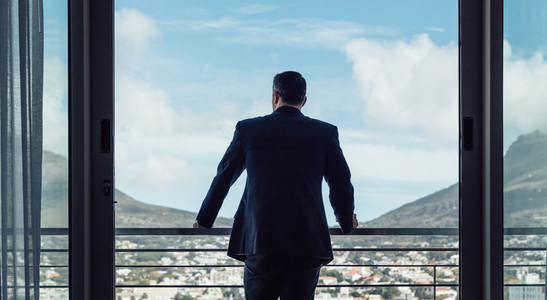 Businessman standing by hotel room balcony