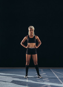 Female sprinter standing on a running track