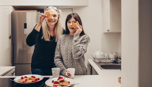 Smiling women standing in kitchen holding cookies