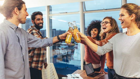 Coworkers celebrating success in office with drinks